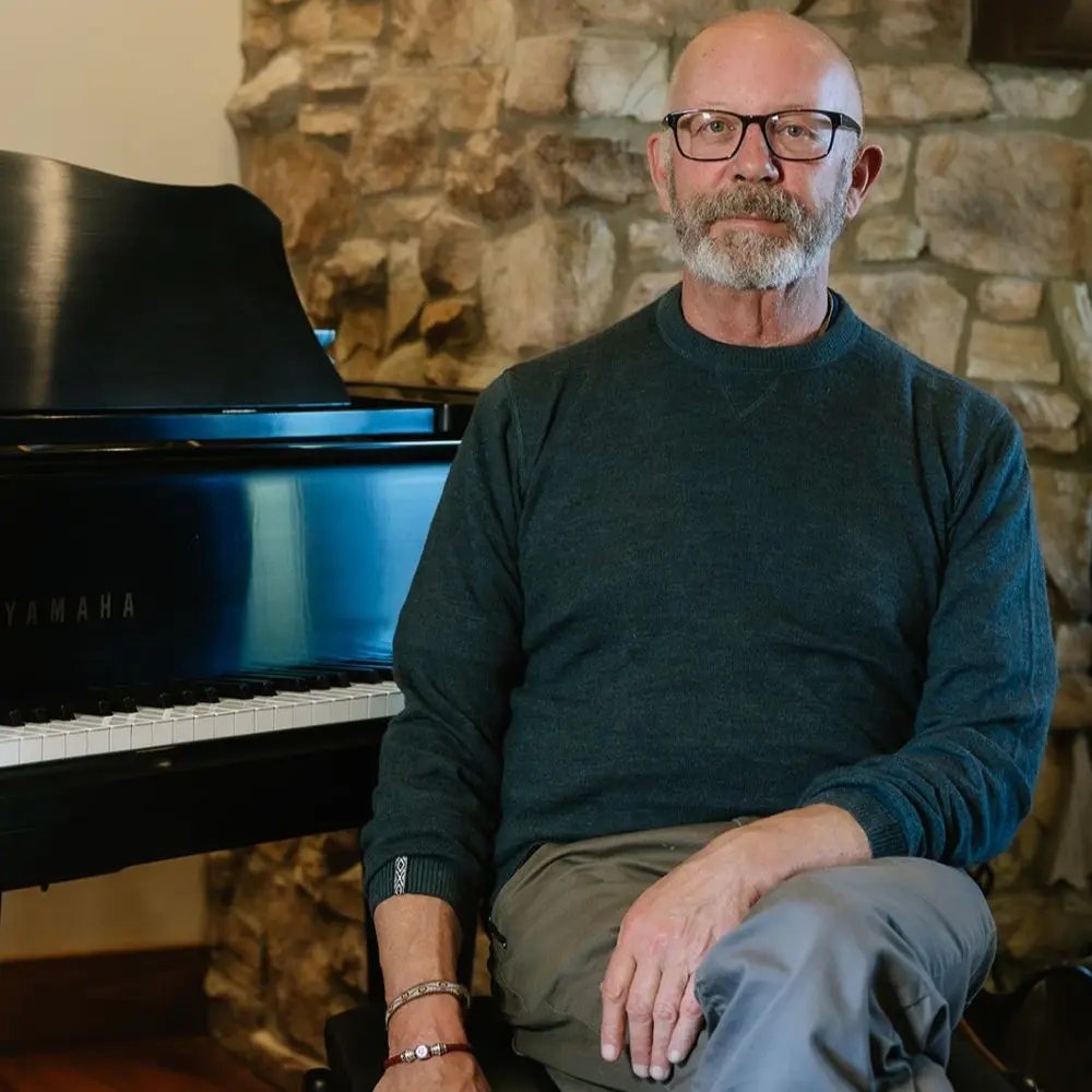 Adron Beene seated indoors, next to a piano.