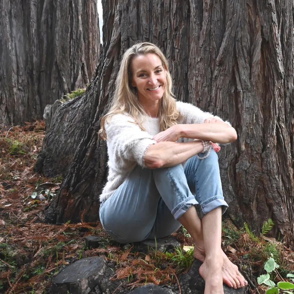 Amy Carroll seated in a forest.