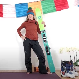 Bridget standing indoors holding her skis