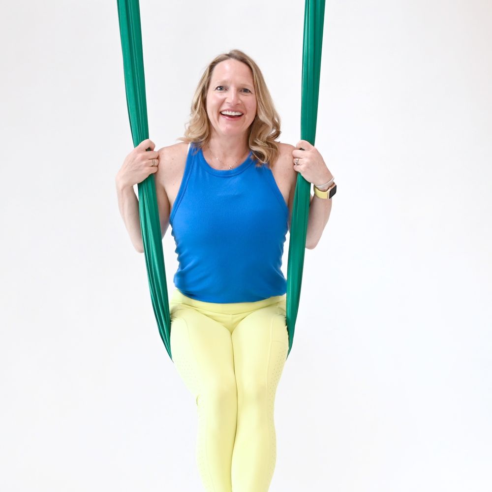 Christy Li is seated in an aerial hammock, smiling.