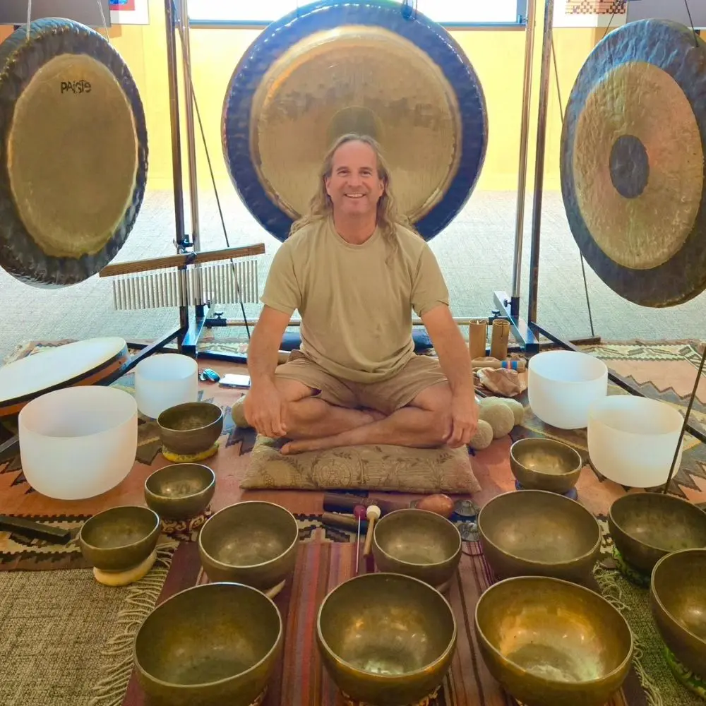 Danny Goldberg smiling in front of brass gongs and sound bowls