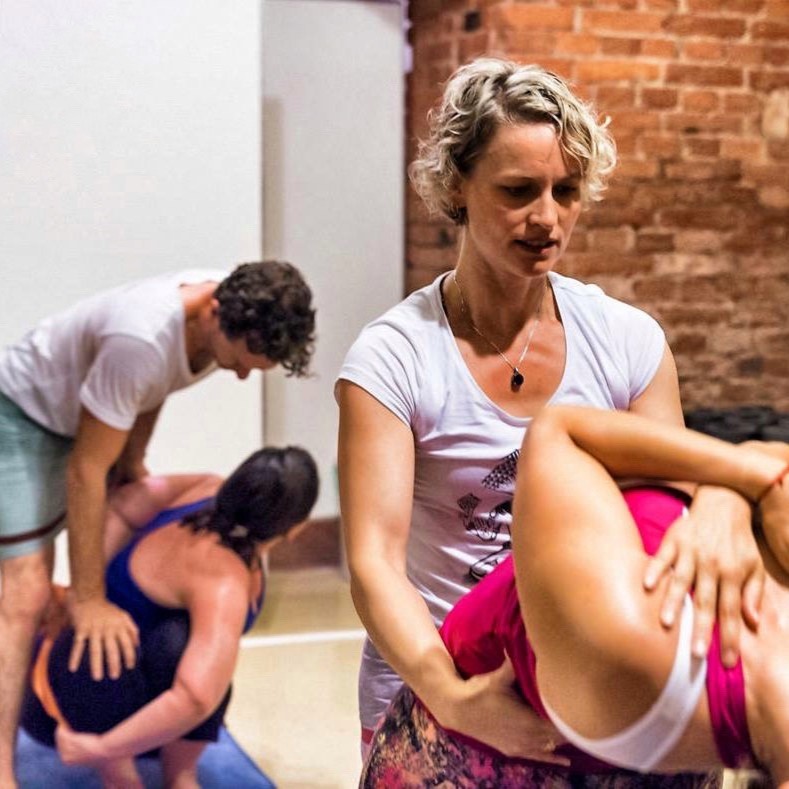 Harmony Slater and Russell Case are each assisting an individual with yoga postures.