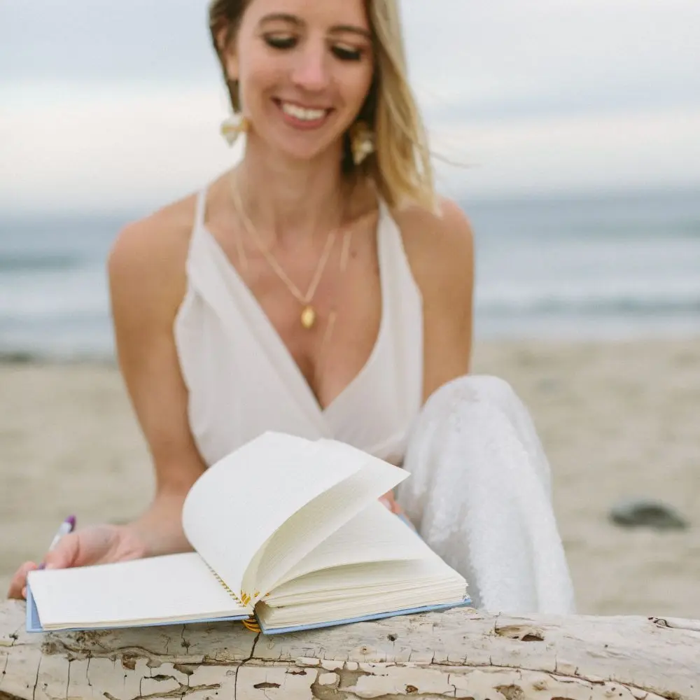 Katie Davidson on a beach with an open journal.
