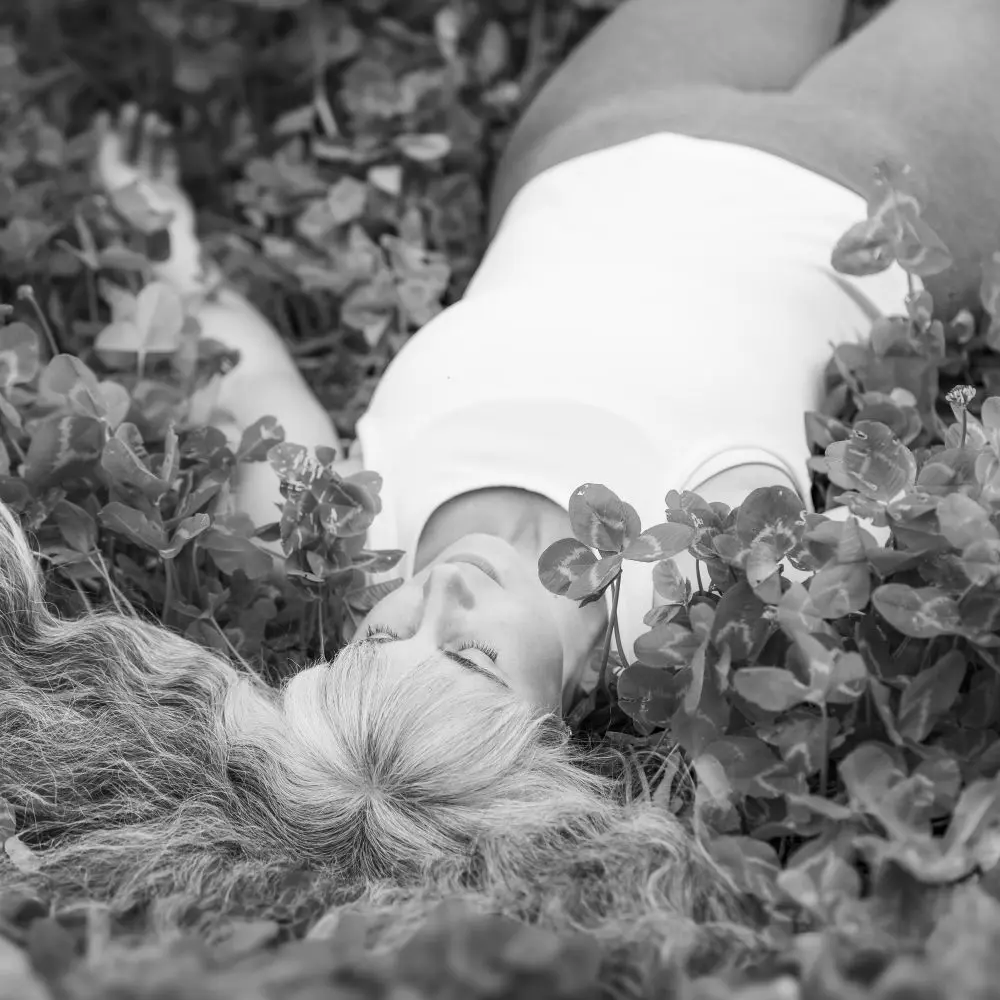 A black and white photo of Kourtney laying in a field of clovers.