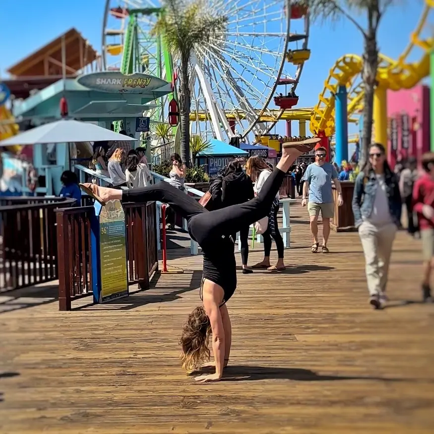 Leslie is doing a handstand while on the boardwalk.