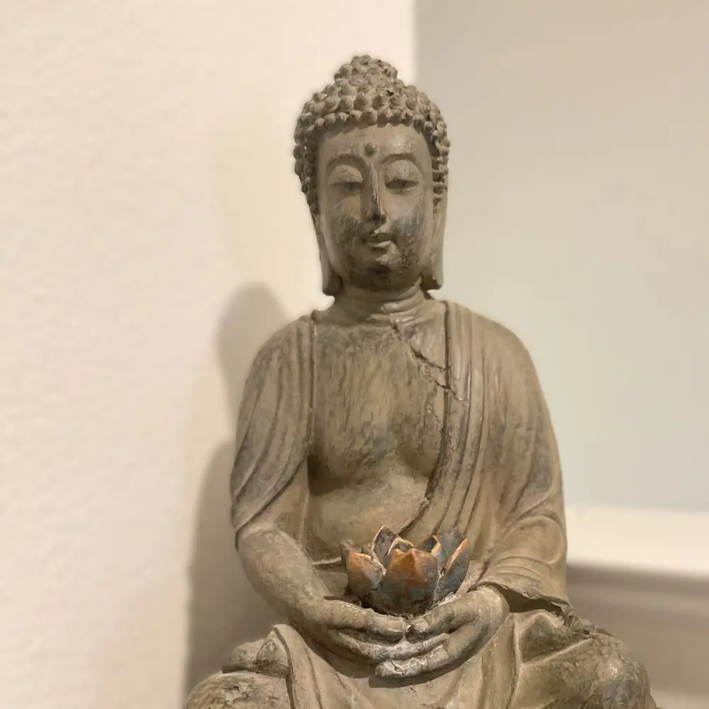 A statue of a Buddha with a lotus flower in its palms.