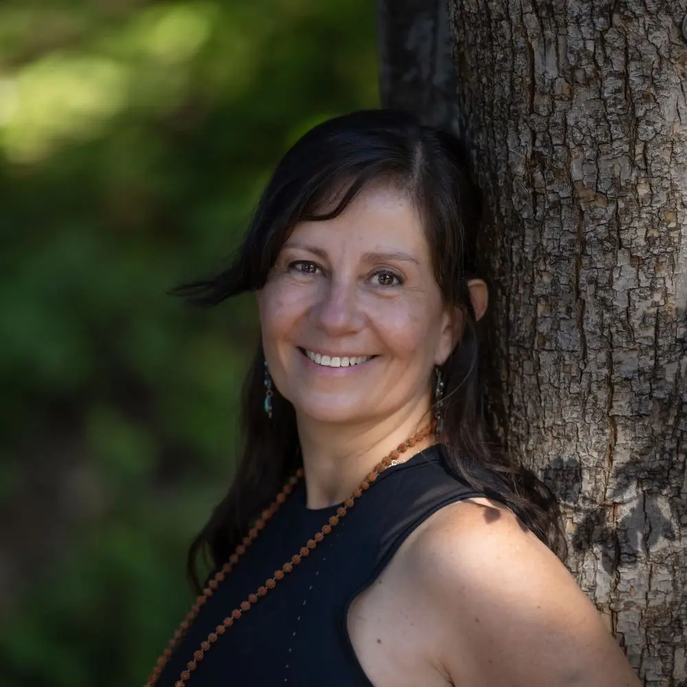 Marcela smiling next to a tree.