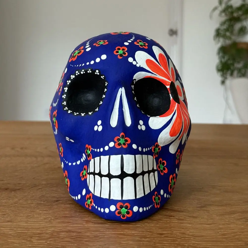 a blue candy skull painted with white and orange flowers