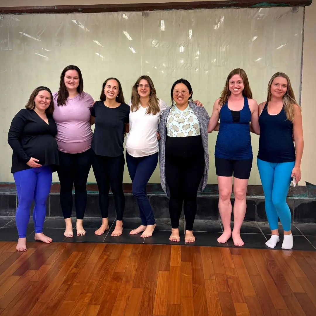 A group of 6 expectant moms pose for a photo with yoga teacher, Marina Poole.