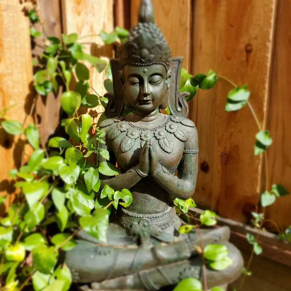 an outdoor buddha statue with hands at heart center
