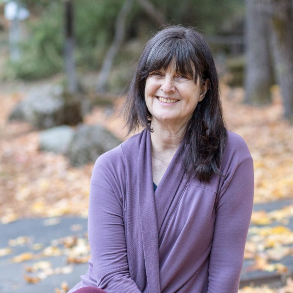 Sarah smiling while sitting outdoors during Autumn
