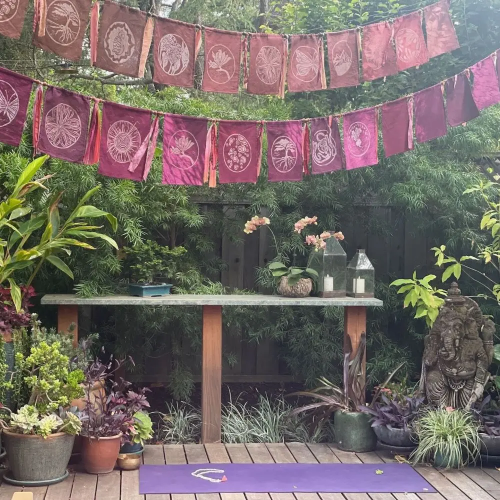 Outdoor deck decorated with prayer flags, plants and statues.