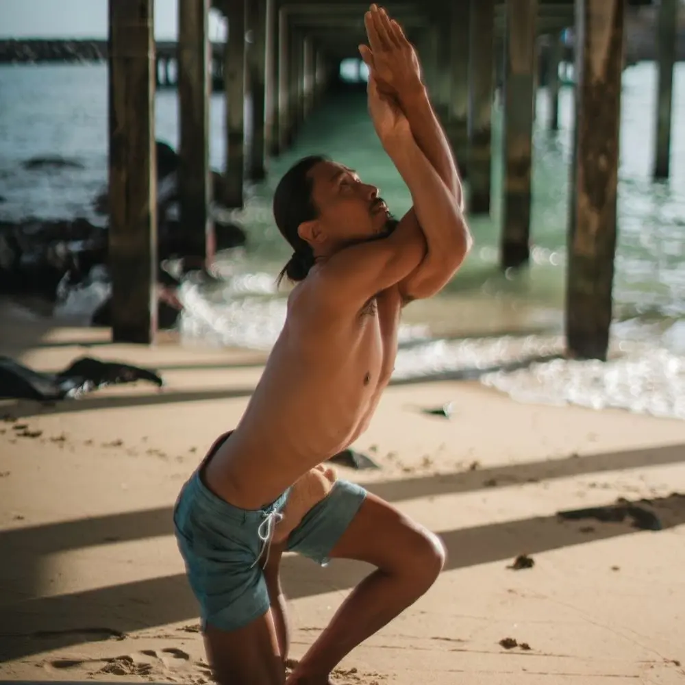 Atsuro Chiba practicing yoga on a beach.