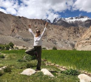 Bridget practicing tree pose in a field, with mountains in the background