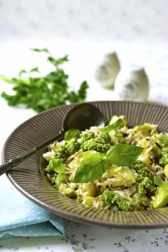 Mix of brown and wild rice with zucchini and basil pesto on a light background.