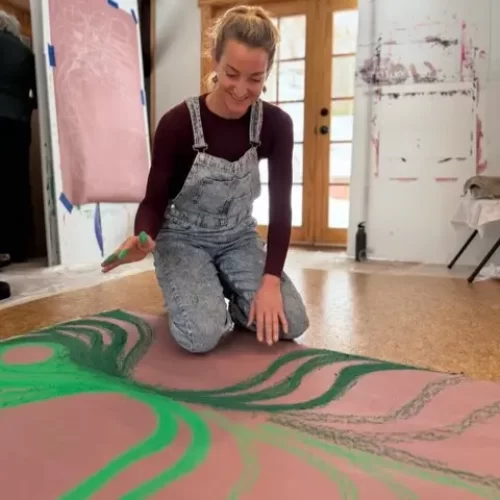 Amy Carroll finding painting on a large brown paper.