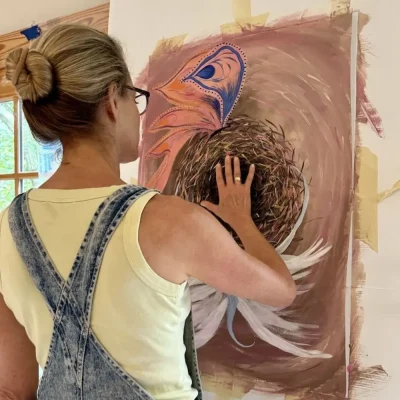 Photo looking over Amy's shoulder, while she touches her painting