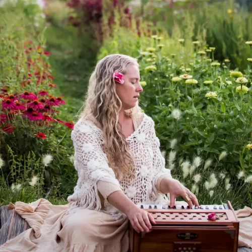 A woman in a field of flowers playing a harmonium.