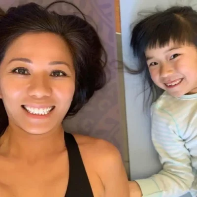 Julie Kwok with a child, on a yoga mat