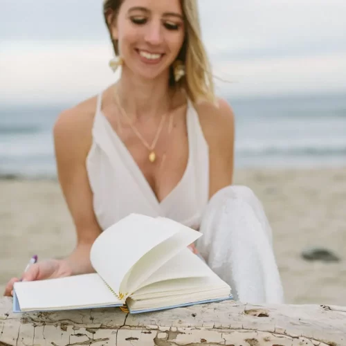 Katie Davidson on a beach with an open journal.