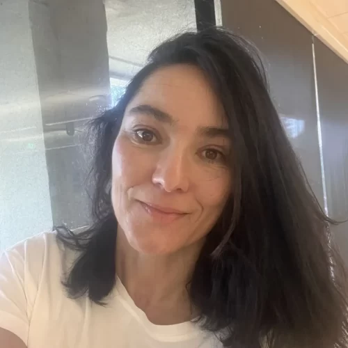 A headshot photo of Monica Torres smiling, wearing a white shirt.