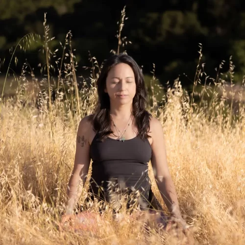 Paulette Sato meditating in a field