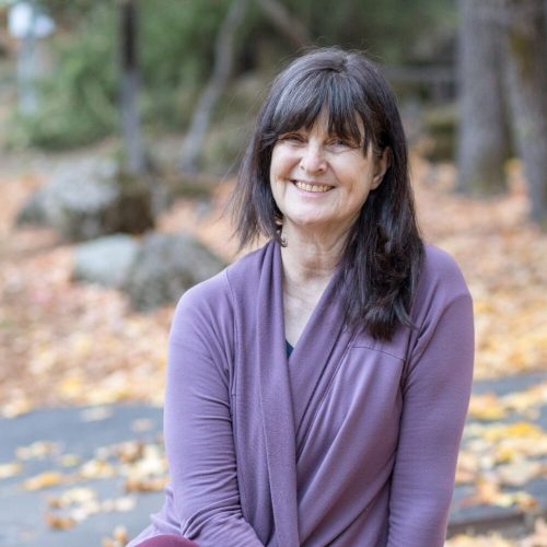Sarah smiling while sitting outdoors during Autumn