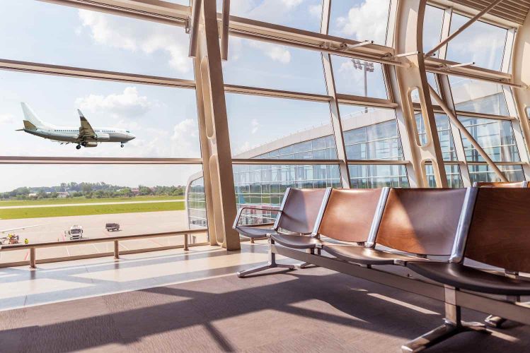 View from the airport lounge to landing passenger aircraft and Car airfield maintenance at airport apron. Summer, Airplane travel concept.