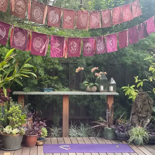Outdoor deck decorated with prayer flags, plants and statues.