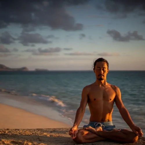 Atsuro Chiba meditating in lotus pose on a beach
