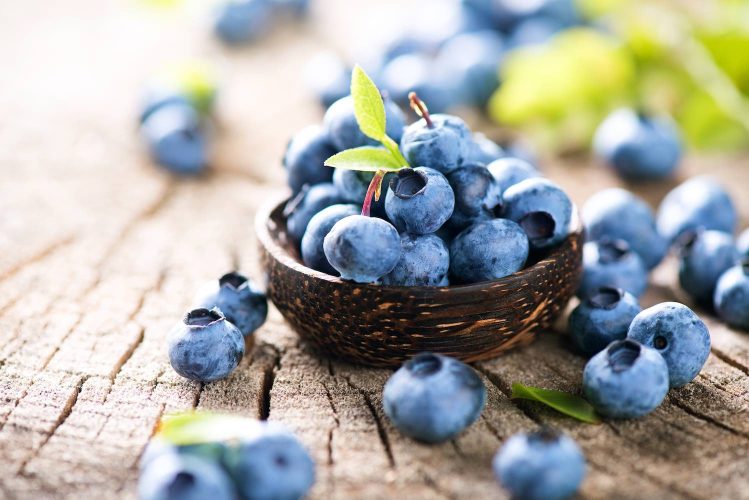 Freshly picked blueberries in wooden bowl, symbolizing antioxidants and healthy nutrition.