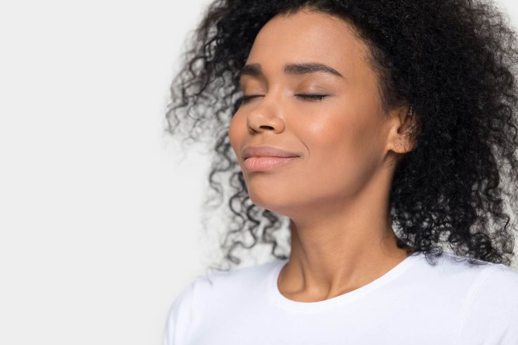 Calm peaceful African American woman breathing deep close up