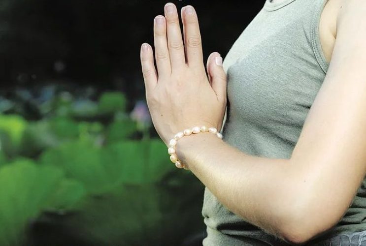 Woman stands with palms together at chest