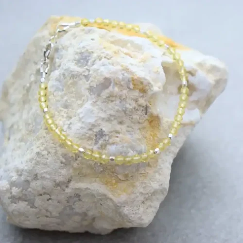 Delicate yellow beaded bracelet on a textured white stone, yoga-inspired accessory.