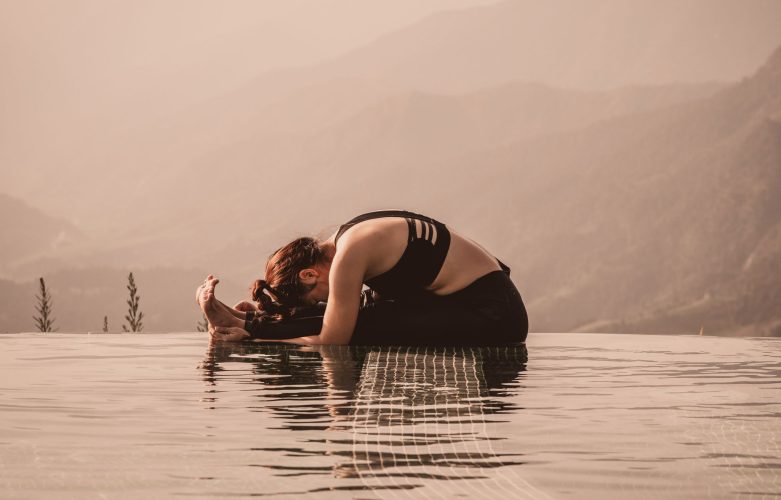 Beautiful Asian woman practice yoga sitting forward fold pose on the pool above the Mountain peak in the morning in front of beautiful nature views,Feel so comfortable and relax with yoga in holiday