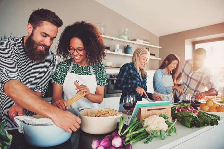 Five friends cheerfully cooking for an upcoming party