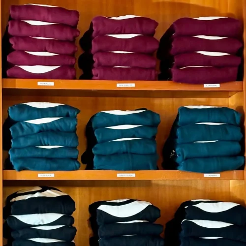 Three rows of shelves, each with three stacks of neatly folded Breathe Together Yoga hoodies.