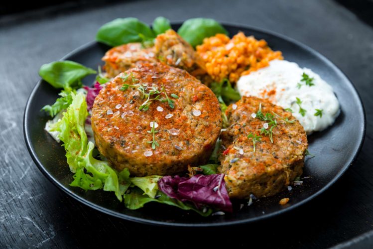 Close up photo of plated kitchari burger on a bed of lettuce, sprinkled with sea salt.