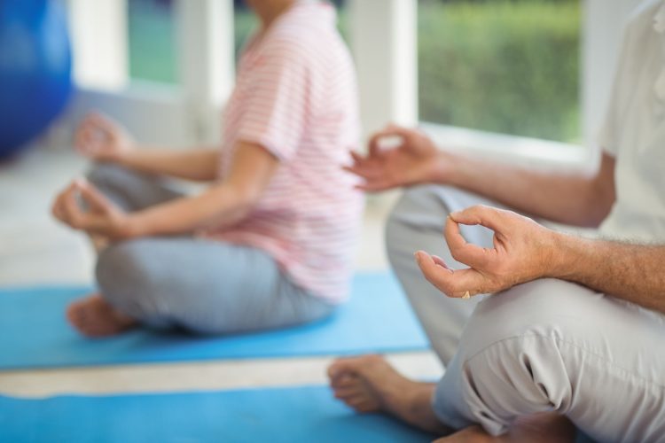 Mid-section of senior couple performing yoga on exercise mat