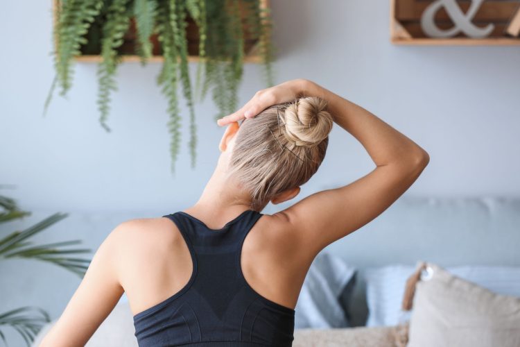 Young woman training at home, back view