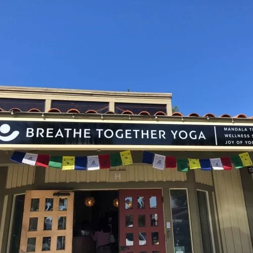 the outside of the studio, breathe together yoga, showing the open front door and a blue sky in the background