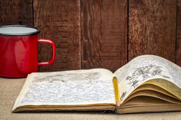 Vintage expedition journal with a metal cup of hot tea - handwriting and drawing in pencil from a kayak trip in Poland in summer of 1974.