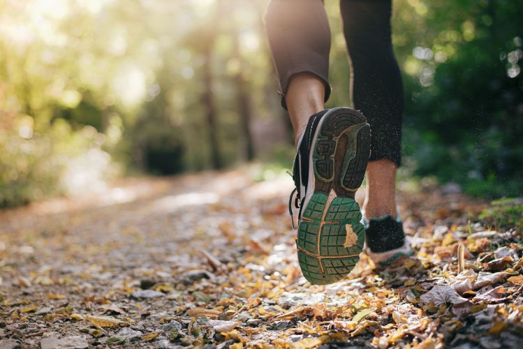 Closeup of running shoe of the person running in the nature with beautiful sunlight.