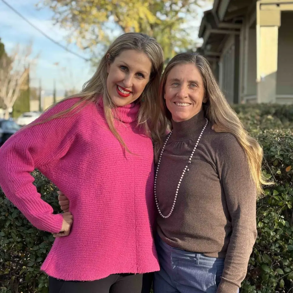 Erica and Bridget standing outside, side by side, smiling.