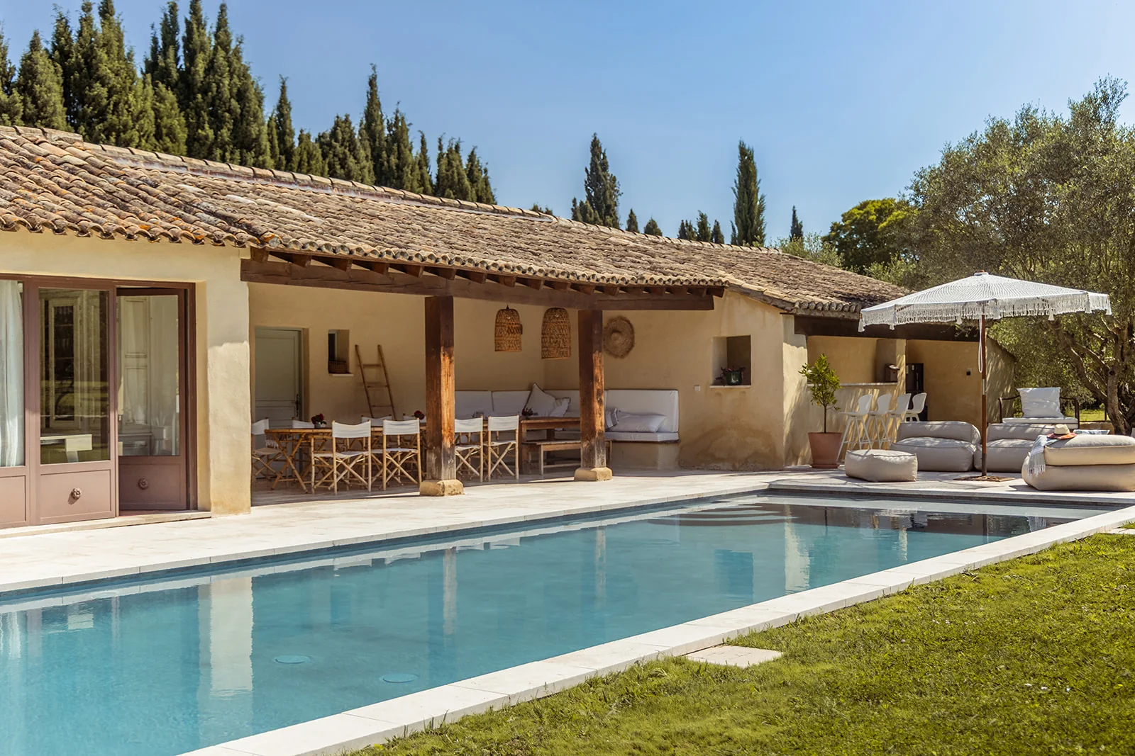 poolhouse in france, with a clear blue pool and places to sit