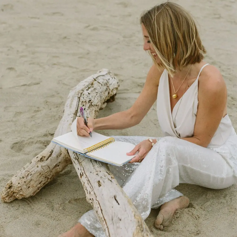 Katie Davidson journaling on a beach.
