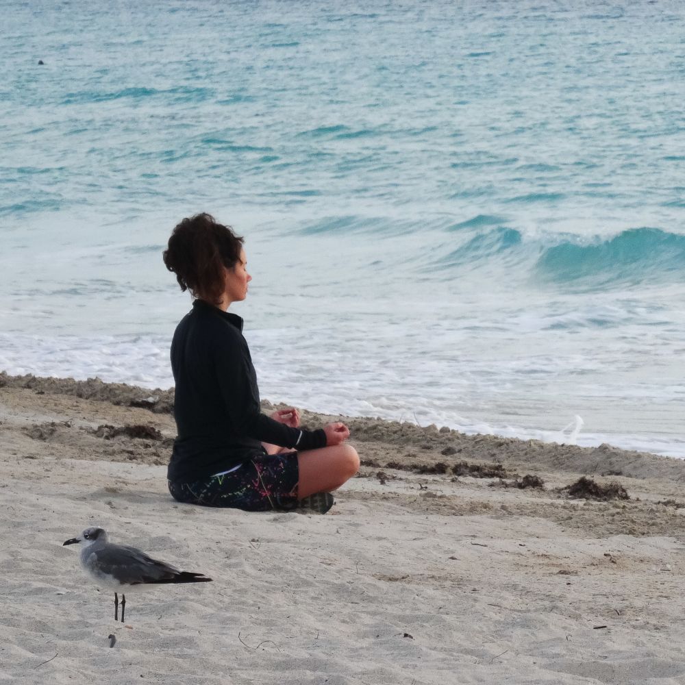 girl meditating on beach