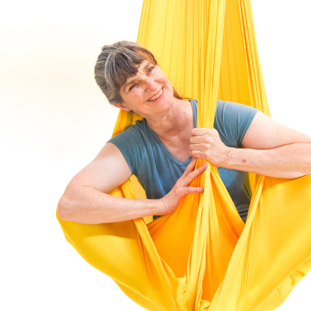 sarah in a yellow aerial hammock smiling
