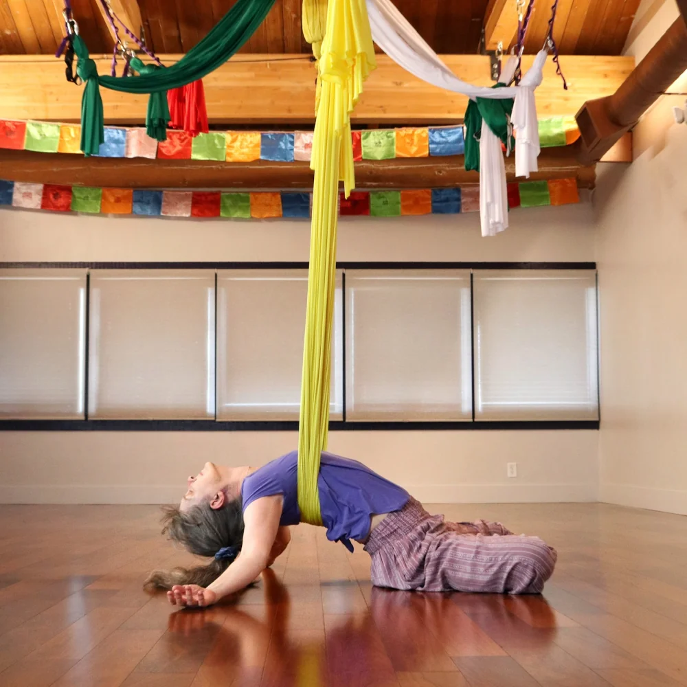sarah in a yellow aerial hammock doing a backbend