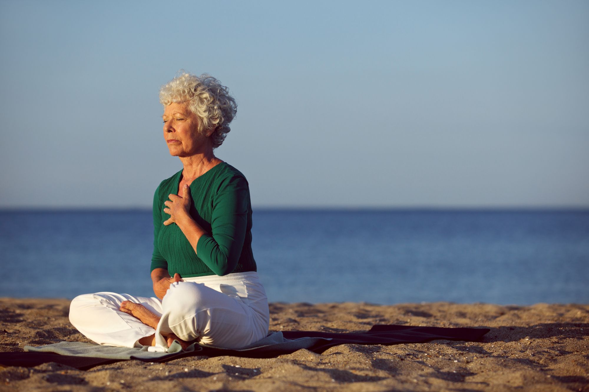 Senior woman in meditation by the ocean